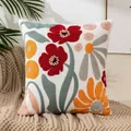 Square white pillow cover with bold red floral embroidery on beige knit throw - Floral Collection
