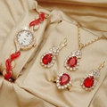 Close-up of gold jewelry set with red teardrop gems and luxury quartz watch - Red