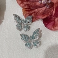 Détail de boucles d'oreilles papillon avec gemmes bleu clair sur tissu ivoire texturé - 13# Style Papillon Gemme Bleu Clair