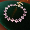 Close-up of pink oval-cut zircon bracelet with lobster clasp on dark green velvet - Pink