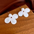 Primer plano de los pendientes de flor blanca con perla en un soporte de madera elegante - Estilo Perla Flor Blanca