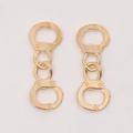 Detailed view of creative gold-tone handcuff-shaped alloy jewelry charms on a white surface - KC Gold
