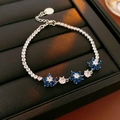Close-up of zircon flower bracelet with blue and white stones on black leather - Blue Zirconia / Silver