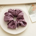 Detail of premium satin scrunchie in mauve with silk texture and round metal logo charm - Purple