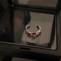 Silver open ring featuring three small red gemstones on a dark luxury jewelry box - Plum Blossom Style (围绕梅花戒指)