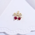 Macro shot of gold cherry pendant with red heart crystals on a white wavy tray - Gold Bowknot Cherry