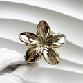 Detailed view of a golden frangipani metal hair claw clip with a glossy polished finish - Frangipani / Rose Gold