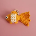 Handmade crochet goldfish keychain in orange and white yarn on pink background - Orange Goldfish