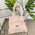 Detail showing pink canvas tote bag with ruffle trim and woven texture on a clear chair - Pink