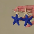 Close-up of blue raffia and gold starfish drop earrings for beach vacation. - Seastar Pendant Style / Gold-Blue