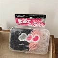 Dettaglio di elastici per capelli multicolori usa e getta in scatola trasparente su legno - Stile Pisello