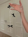 Detail of long pearl necklace with black bows held by hand showing length and drape - White - Black Bow