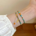 Gros plan de bracelets bohèmes empilés avec breloques dorées et perles de résine colorées - Style de Strass de Caractère de Fortune