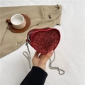 Sparkly red heart-shaped chain bag with glitter texture held against a beige blazer - Red