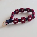 Detailed view of handmade woven floral phone strap in deep blue and wine red yarn - Burgundy