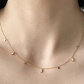Elegante gouden kwastjesketting met druppelvormige kristallen op een vrouwenhals - Goud