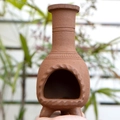 Close-up of a rustic terracotta palo santo holder with engraved patterns and tripod base - Terracotta Chimney