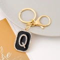 Detailed view of golden letter Q keychain with rhinestones and black enamel on a plate - Letter Q