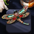 Vintage dragonfly brooch featuring colorful rhinestones on a blue jewelry box - Green & Red