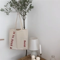 Minimalist beige canvas tote bag with red typography print hanging in a cozy room - Zipper Style / Beige