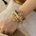 Detail of 4-piece bohemian beaded bracelet set with gold butterfly charms on model - Green