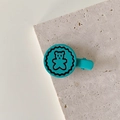 Dettaglio della clip per capelli blu con motivo a orsetto su superficie in marmo - Orso Verde