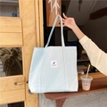 Detail view of a light blue canvas tote bag with a minimalist white square label - Light Blue