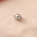 Close-up of a spherical silver magnetic clasp for DIY jewelry on pink textured fabric - Steel
