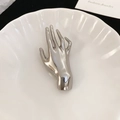 Makroaufnahme der silbernen Handbrosche mit spiegelpolierter Oberfläche und Metalldetails - Silber