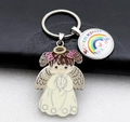 Close-up of Schulkind rainbow charm and angel pendant on a metal keychain - Off White