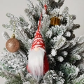 Détail d'un gnome de Noël tricoté rouge et blanc sur une branche de sapin enneigée - C2-1 Petit Ornement Rouge Style E (Bonnet Tricoté à Pois Rouges et Blancs)