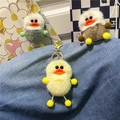 Dettaglio di portachiavi a forma di anatra in peluche con fibbie dorate su denim - Giallo