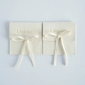 Beige microfiber square jewelry pouch with a ribbon tie and embossed logo detail - 8x8cm / Off White