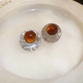 Vista dettagliata di orecchini in resina ambrata con trama in argento martellato - Perno in argento - Orecchini a bottone tondi grigio caffè