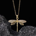Close-up of golden dragonfly pendant necklace with crystal wings on dark rock base - Style K-Gold Half-hollow Pave