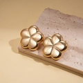 Macro view of gold flower earrings with metallic mirror finish on textured stone - Gold