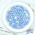 Macro shot of light blue ceramic fish beads with iridescent glaze in a white plate - Light Blue