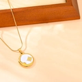 Detailopname van de gouden zon- en maan-hanger ketting op een houten standaard - Witte Schelp Ster Maan Ketting
