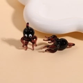 Detailed view of handmade red and black glass octopus charms on a white ceramic tray - Purple