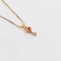Close-up of gold-plated key pendant featuring orange heart crystal and micro-pavé stones - Red