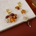 Detalle de pendientes de ámbar asimétricos con flores doradas y borlas de resina - Poste de plata para pendientes - Café