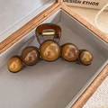 Vue détaillée d'une pince à cheveux en résine ambrée avec cinq perles rondes et boîte - Pince à cheveux perle ambre / Marron