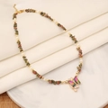 Dettaglio della collana a farfalla con strass colorati e ciondolo a croce su vassoio - 1# Multicolore