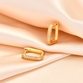 Elegante geometrische Gold-Creolen mit funkelnden Kristallen auf Seidenhintergrund - Gold