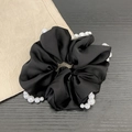 Elegant black satin scrunchie with white pearl trim decoration on a dark wood background - Pearl Style / Black