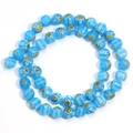 Close-up of sky blue Millefiori glass beads with white stripes and floral patterns - Lake Blue Yellow Flower