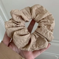 Chouchou élégant en laine beige texturée tenu sur un fond minimaliste et épuré - Style plissé beige / Marron
