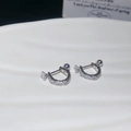 Macro shot of silver U-shaped earrings with zircons on a white ceramic tray - Silver (Silver Pin)