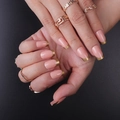 French tip press-on nails with gold edges and matching rings on dark background - FS-21 Pink Base Gold Tip