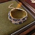 Dettaglio del bracciale con strass a scacchi e base dorata su cuscino verde vintage - Bracciale con Strass Leopardati (Oro)